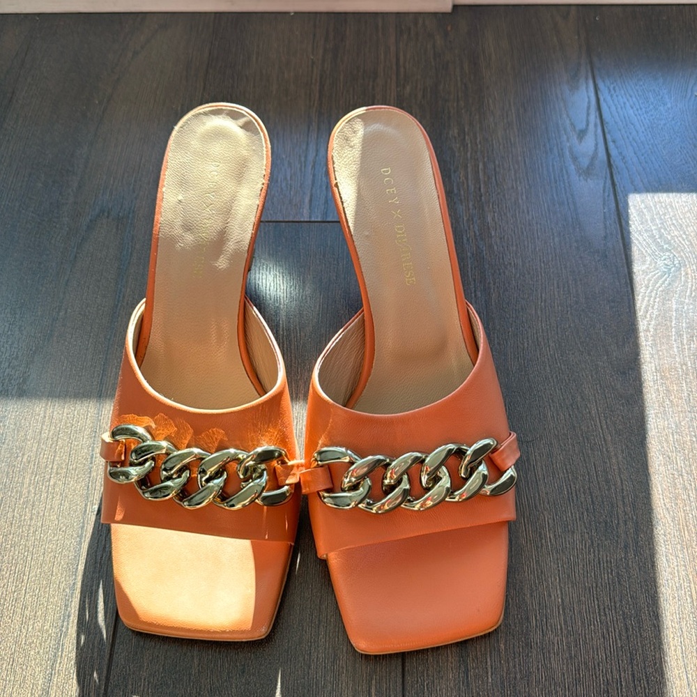 Orange color sandals with gold color chain on it